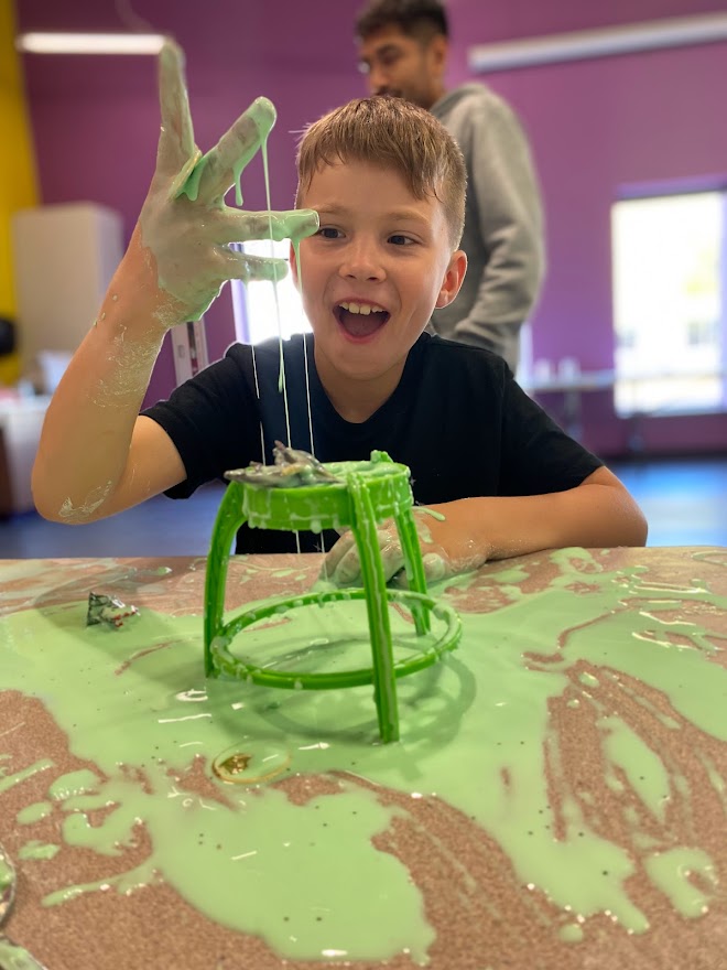 Boy plays with green goop at LaunchPAD Children's Museum