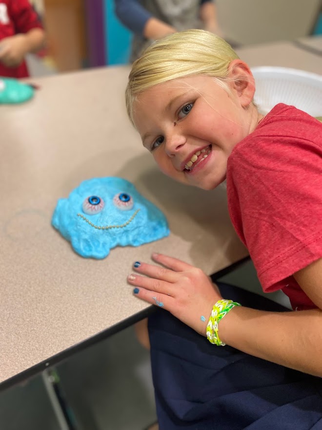 girl smiles next to blue smile craft at LaunchPAD