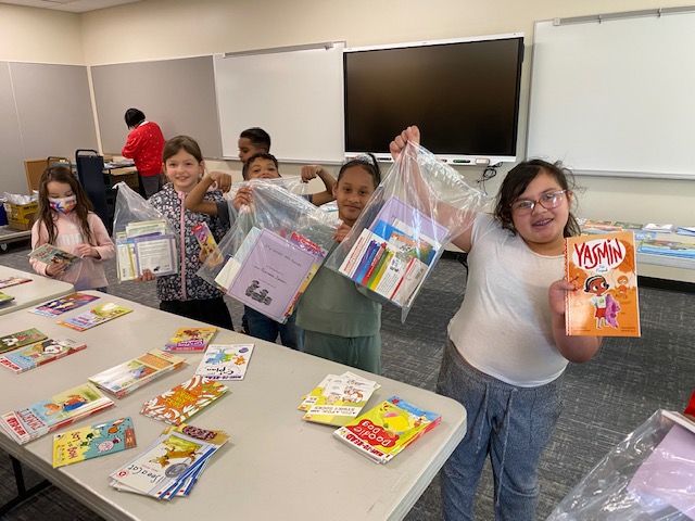 smiling children hold their Page Ahead giftbag of books