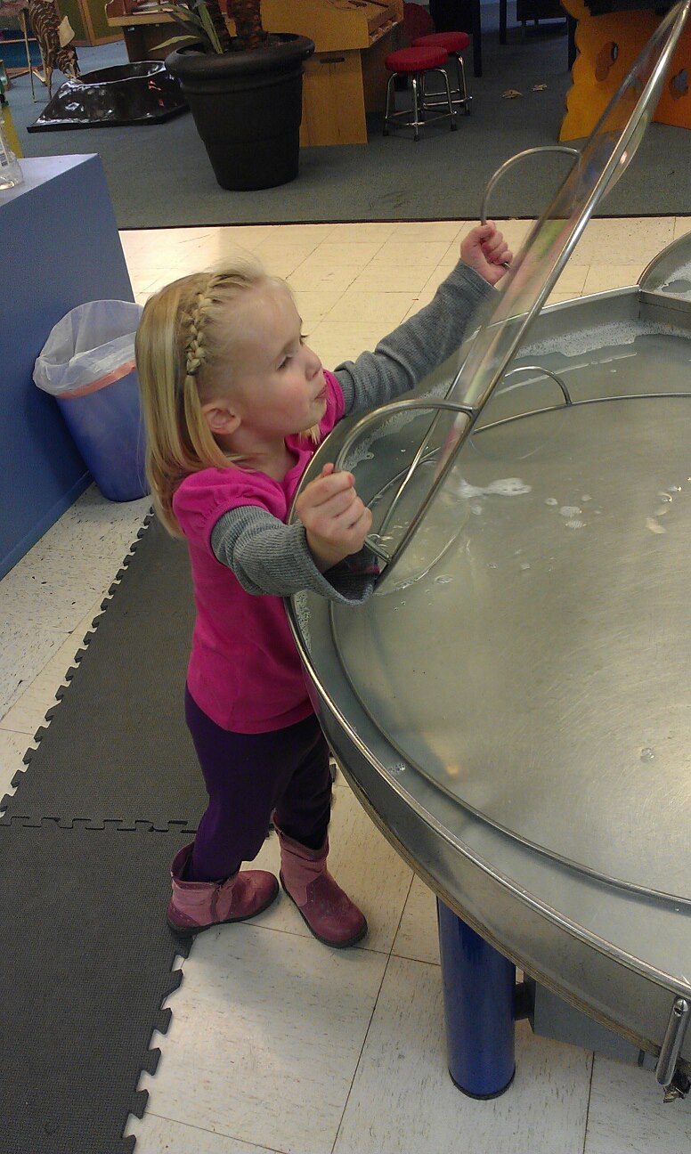 little blond girl makes bubble at The Science Zone