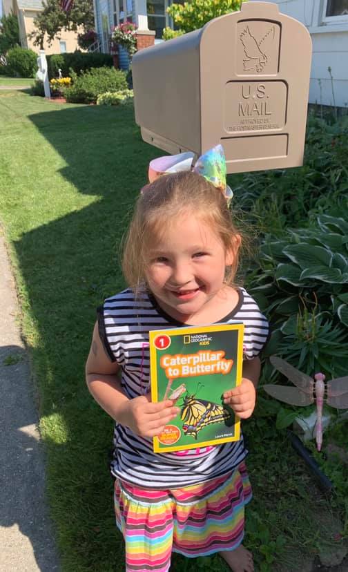 Sophie holds up her new book which just arrived in the mail from Kids Read Now