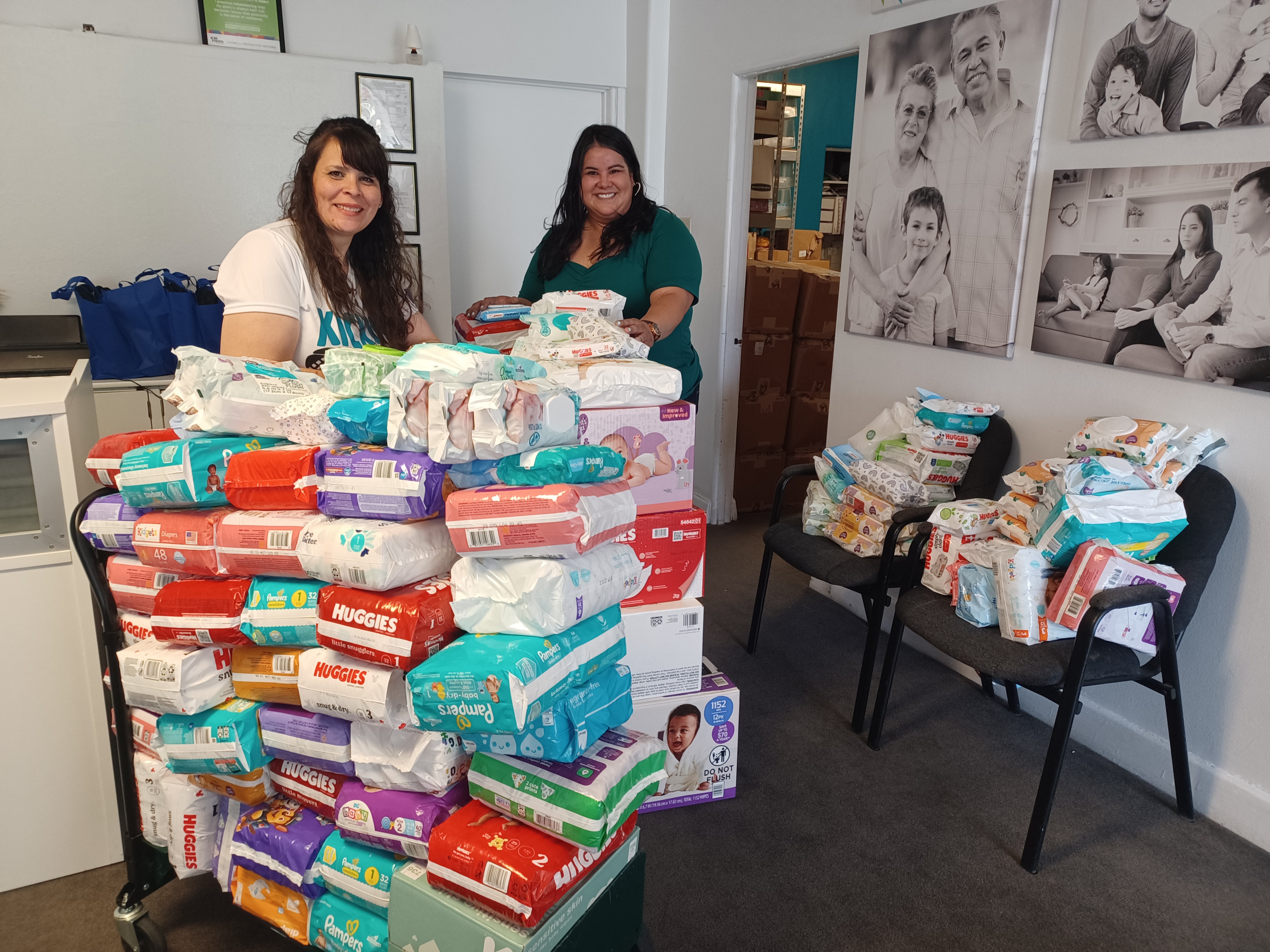 Two EPCC staff with a large donation of diapers stacked on carts inside the office.