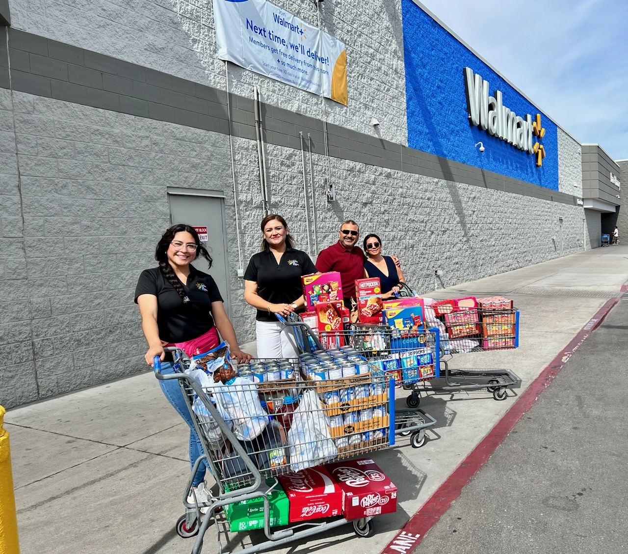 Four EPCC team members with grocery carts full of food outside a Walmart store.