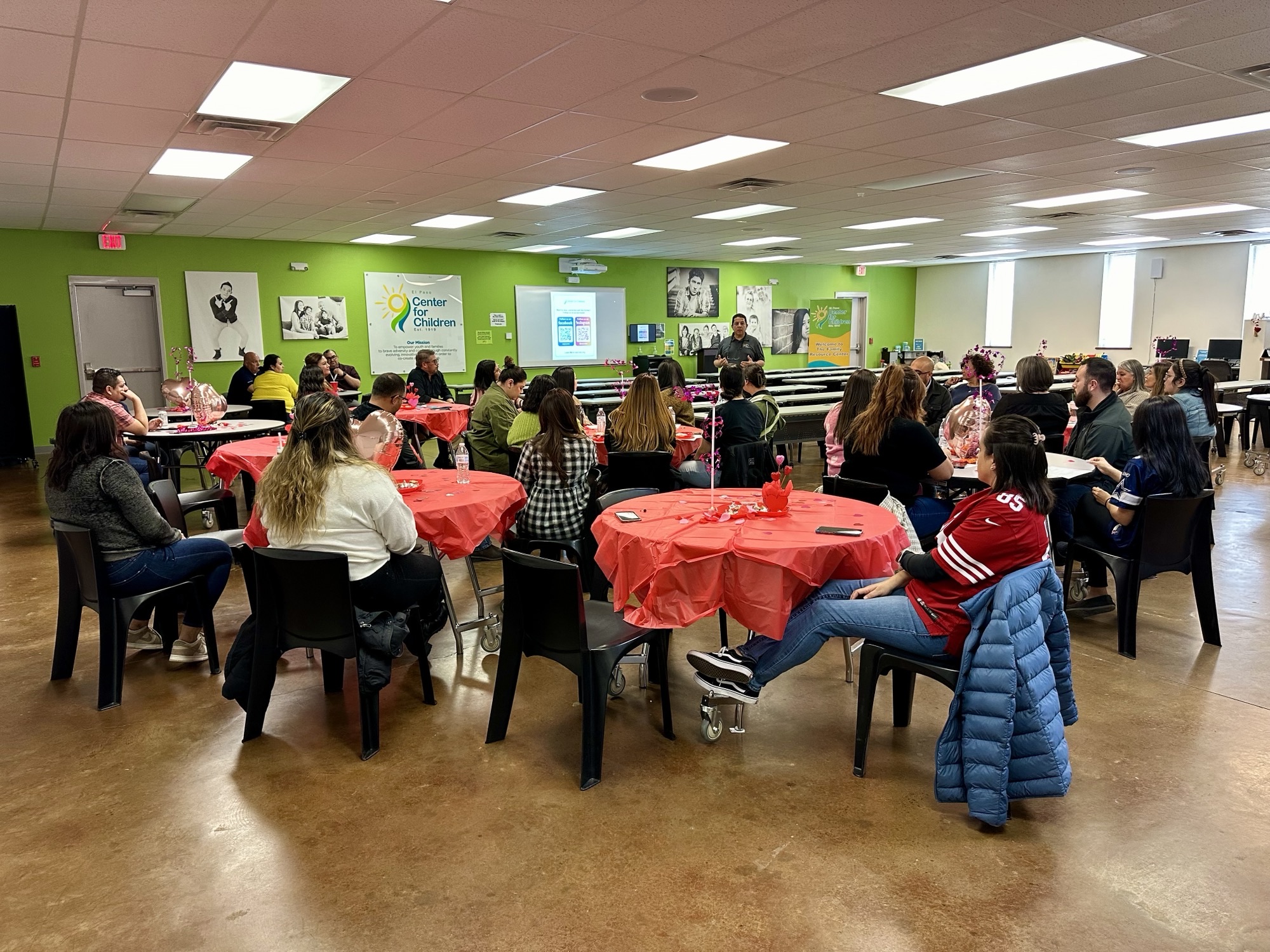 Community event at EPCC with attendees seated at round tables covered in red tablecloths.