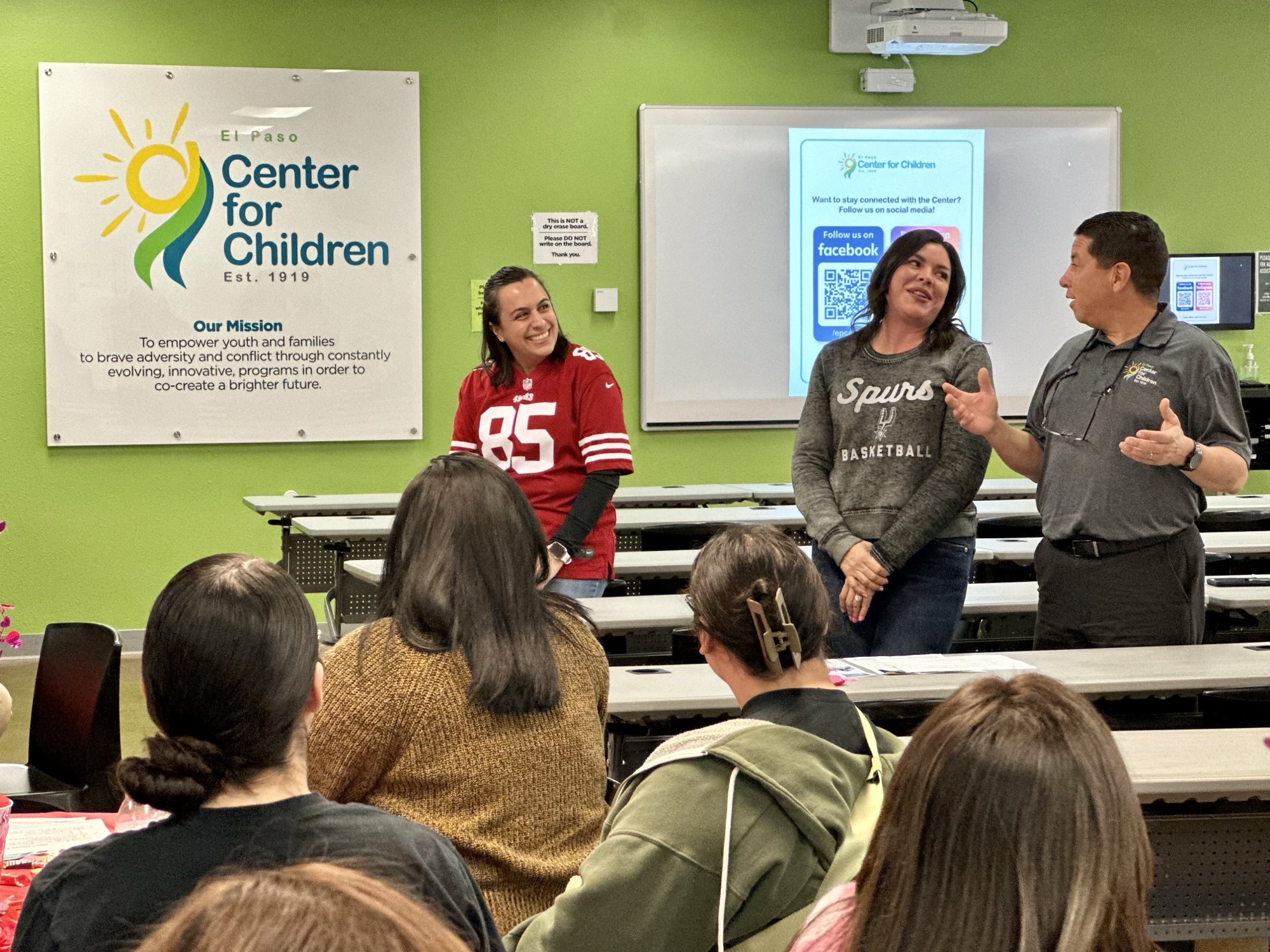 Facilitator standing with two women at the front of a classroom during a workshop at El Paso Center for Children.