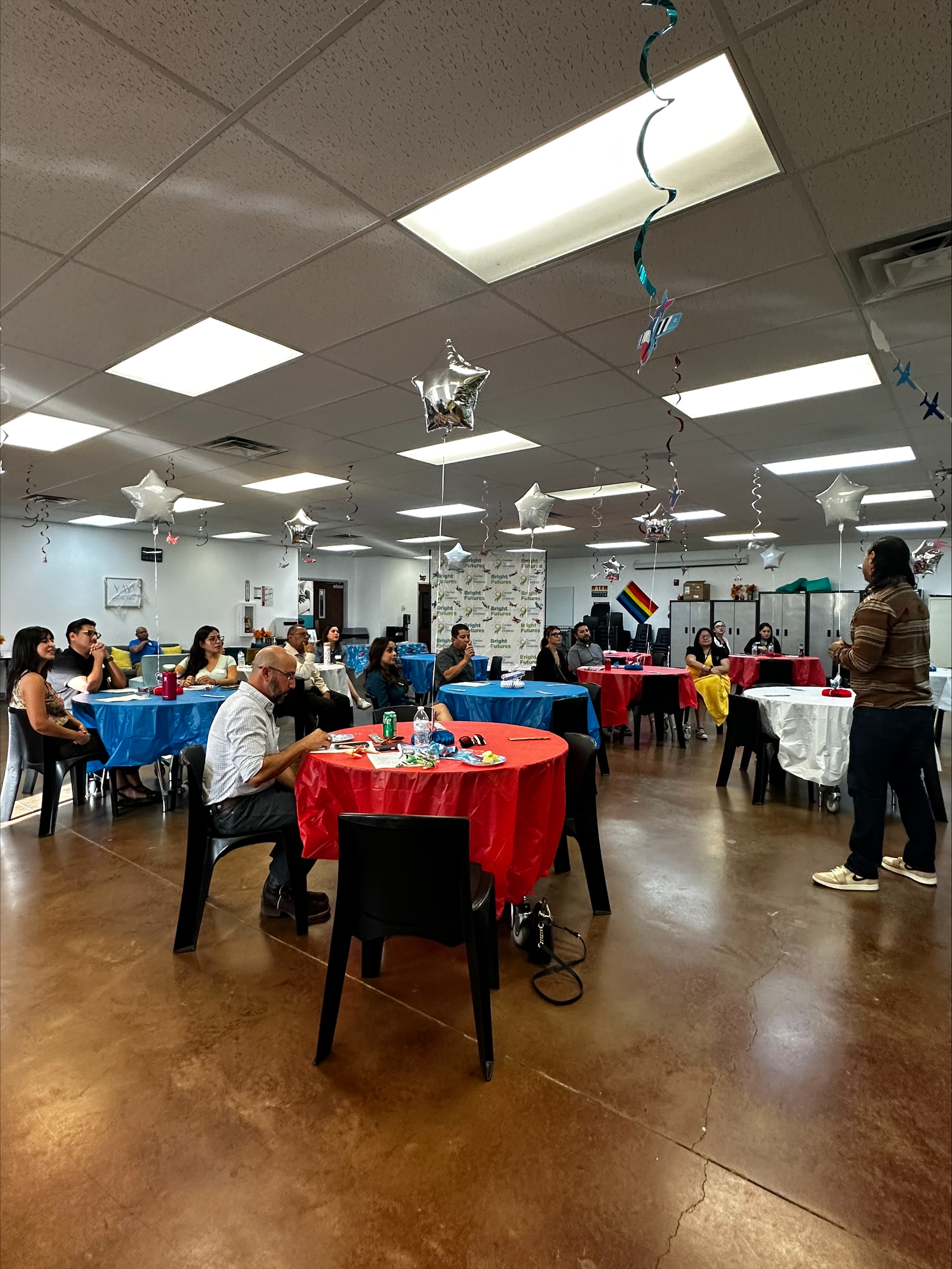 Large group seated at decorated tables during a community event at El Paso Center for Children.