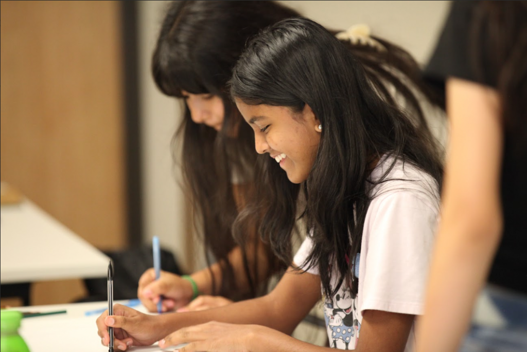 2 smiling girls do homework peak education