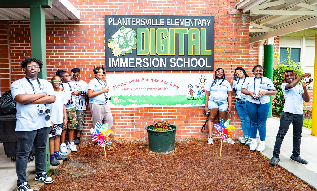 The Village Group teens at Plantersville elementary school with banner "Digital Immersion School" (Plantersville Summer Academy)