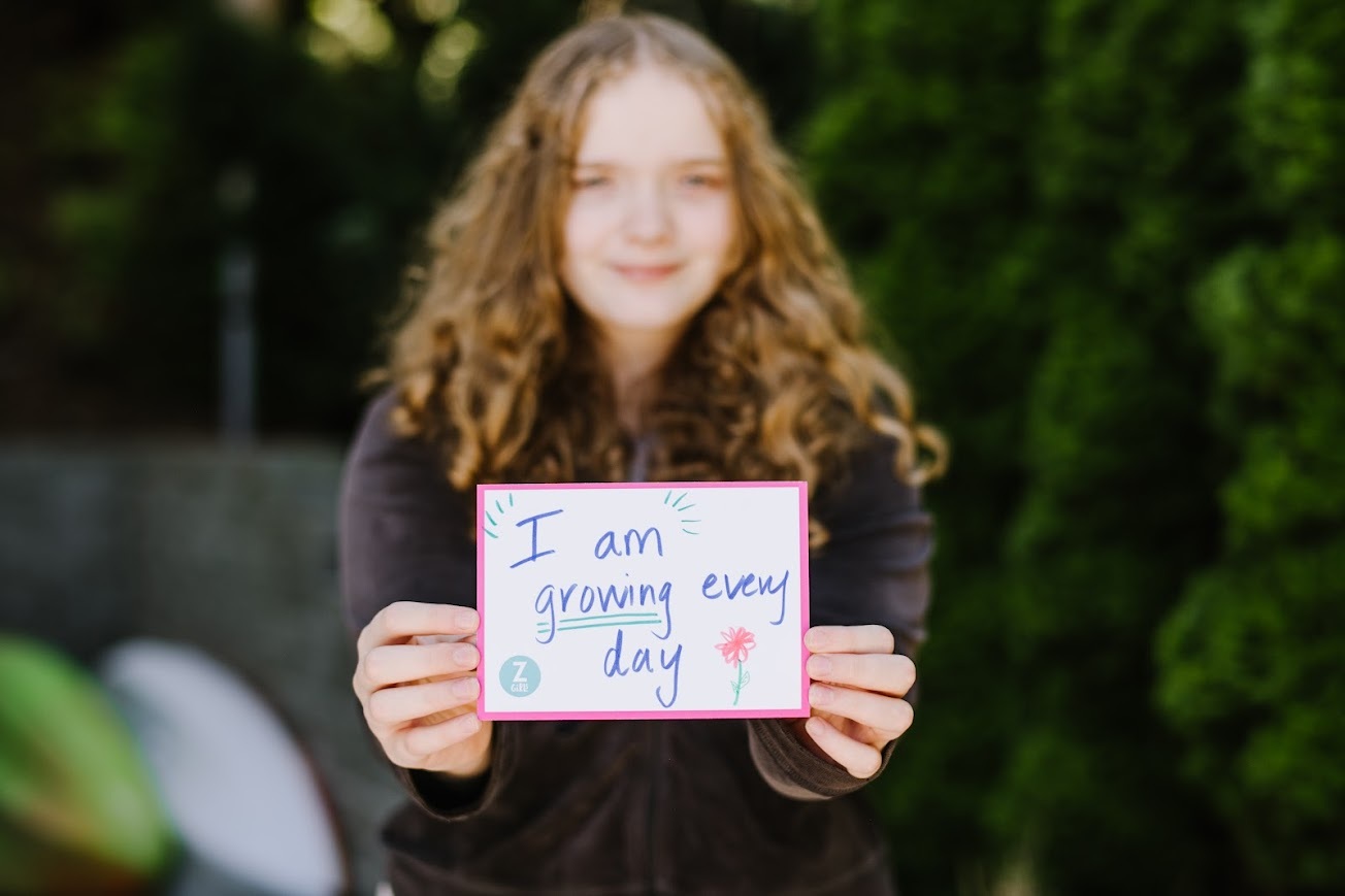 participant holds sign "I am growing every day."