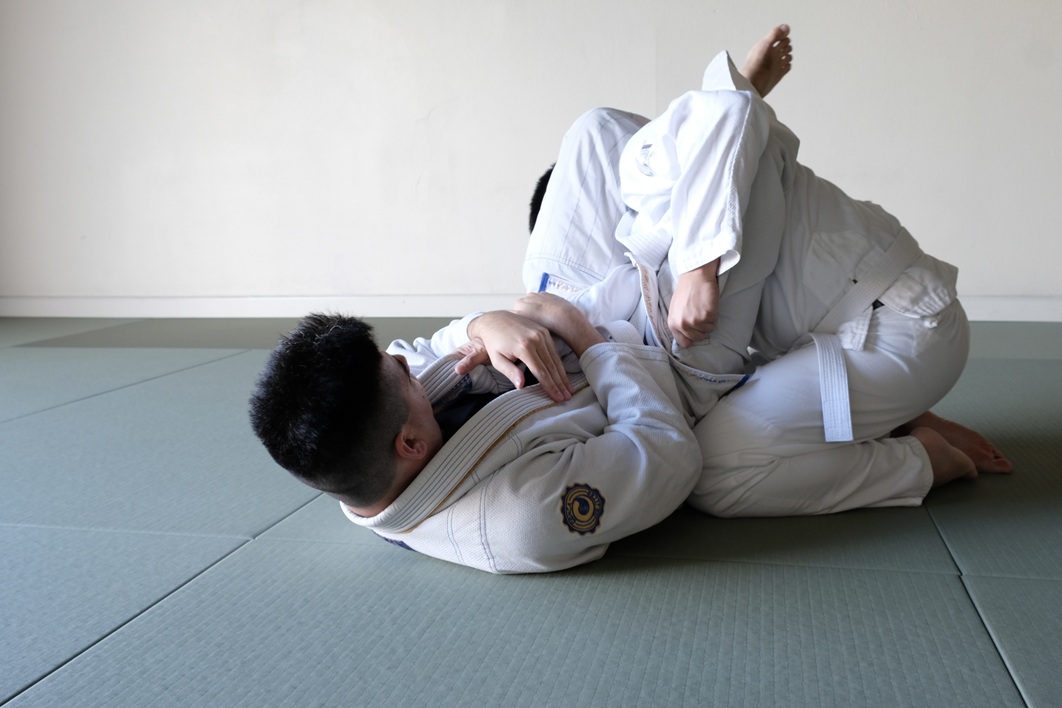Budo Accelerator students practicing Brazilian Jiu-Jitsu grappling techniques on dojo mats.