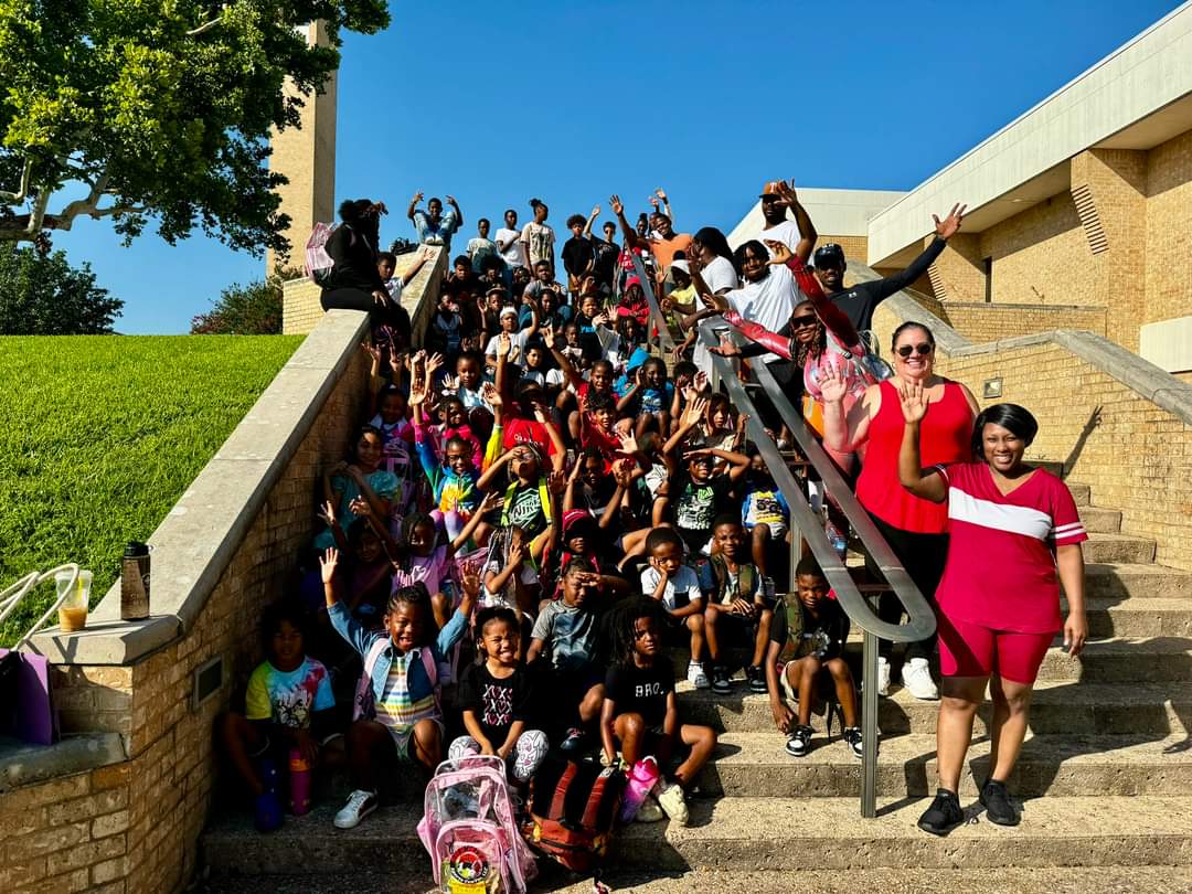 AAYHF kids and volunteers wave group lined up on stairs outside