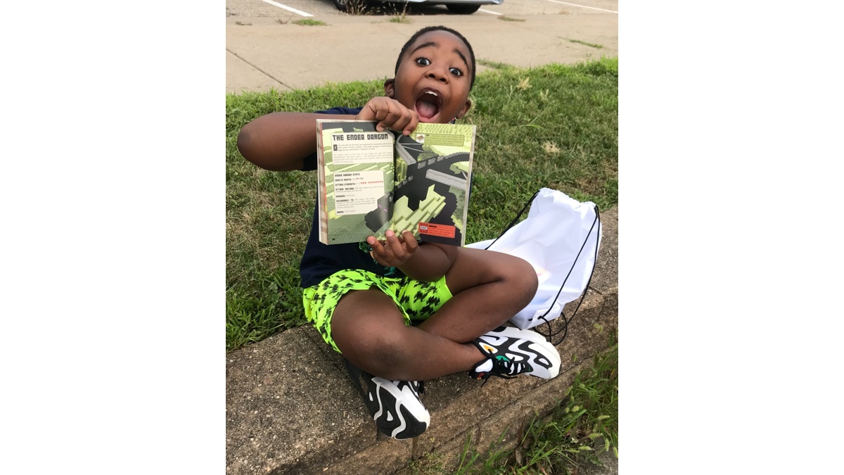 Excited young reader showing a book received from The Free Book Buggie