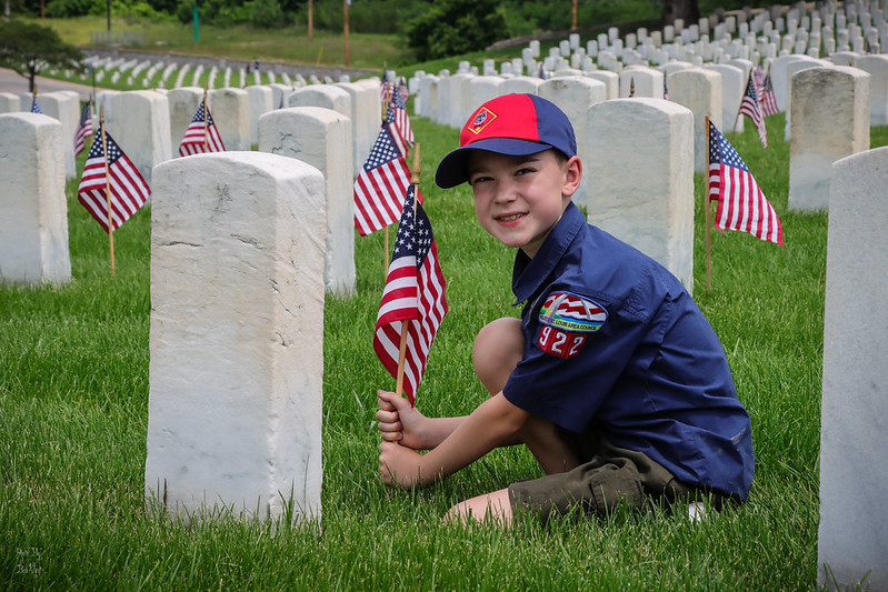 Greater St. Louis Area Scouting young male scout places flag in front of veteran's grave