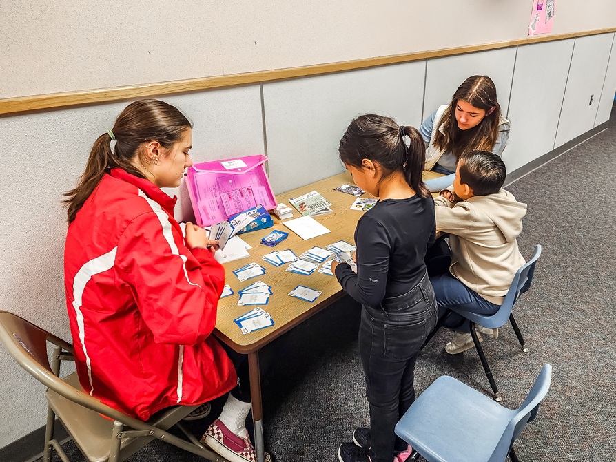 young girls tutor younger children in reading