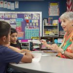 Read With Me Volunteer Programs elderly tutor works with young boy, young girl