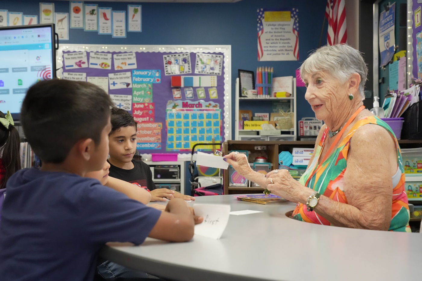 Read With Me Volunteer Programs elderly tutor works with young boy, young girl